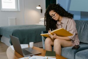 woman with a notebook sitting on a couch at her computer 