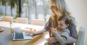 mom on laptop with baby on lap 